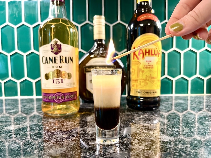 lighting a flaming coffee cocktail layered shot with coffee liqueur