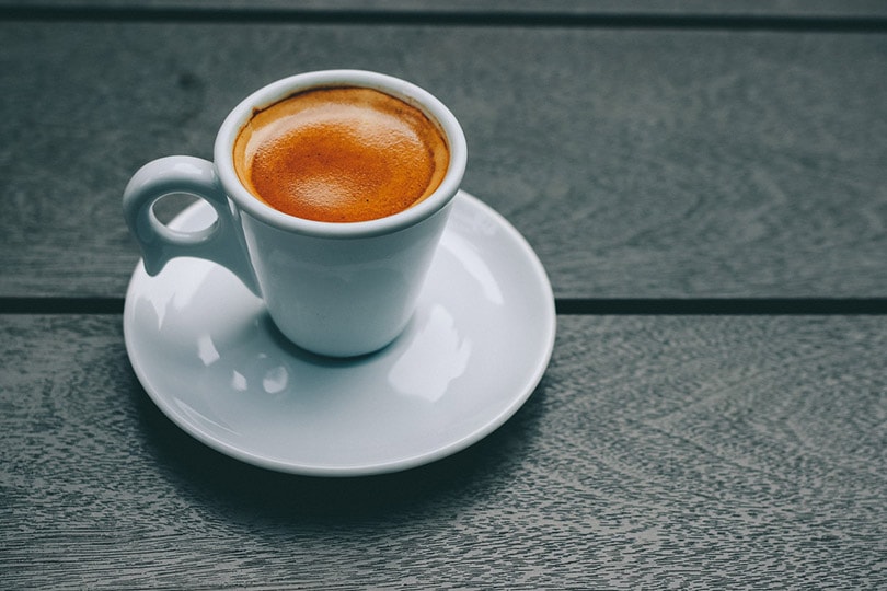 a white ceramic cup filled with coffee on saucer