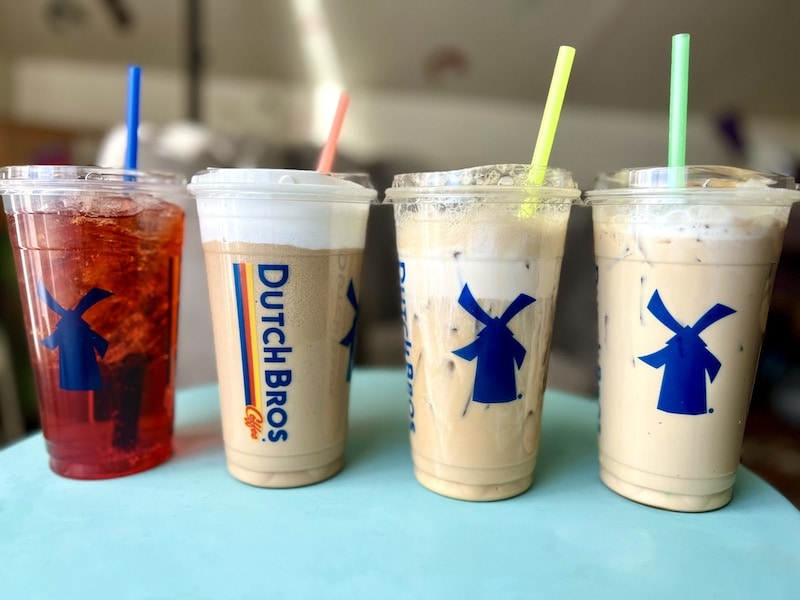 four dutch bros drinks with colorful straws on a table