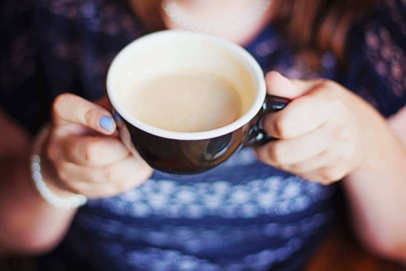 woman holding a black and white ceramic cup