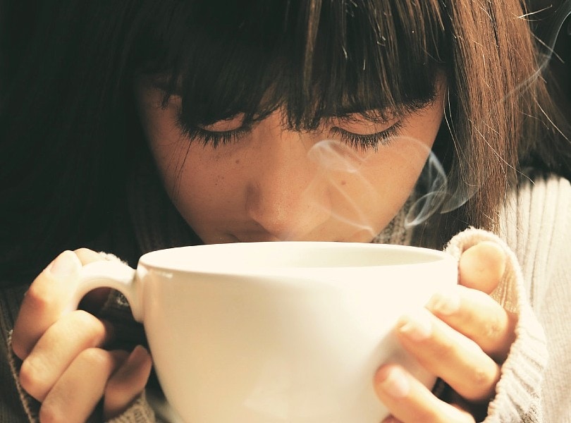 woman holding a white cup