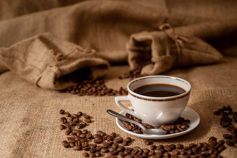 a cup of coffee on a saucer with coffee beans