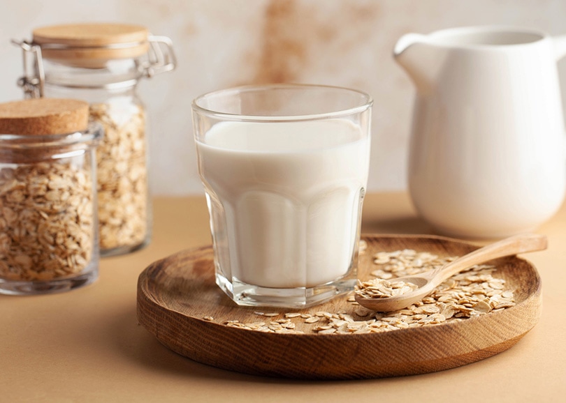 Oat milk in a glass, flakes of baked cereals