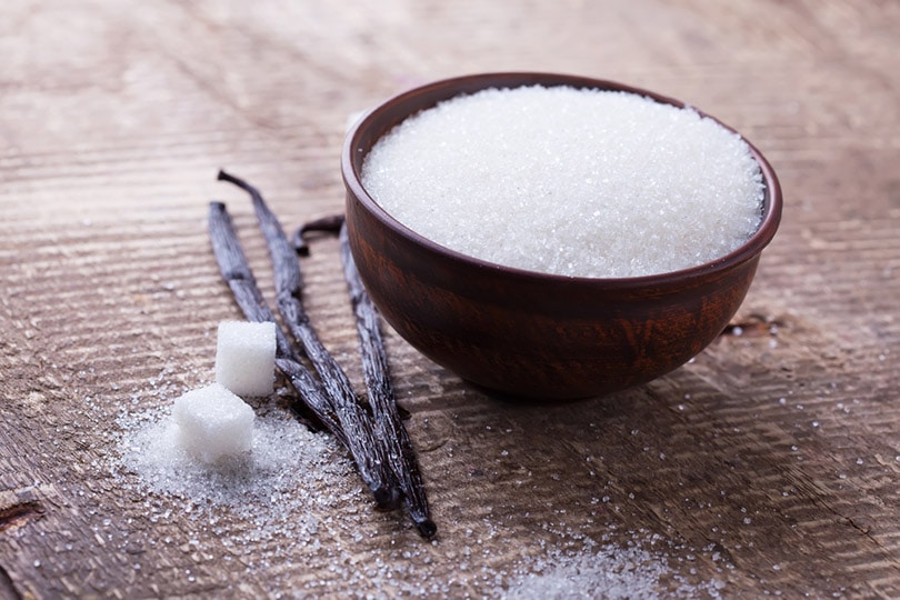 Sugar with vanilla beans on wooden background