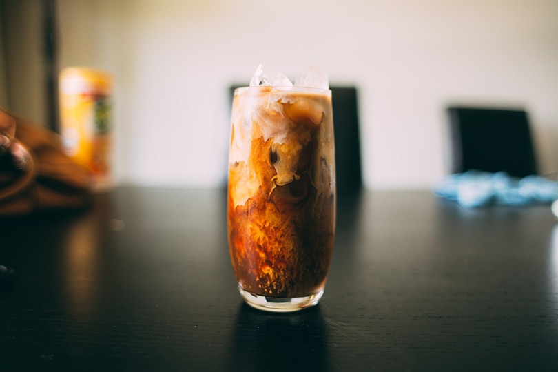 a glass of iced coffee on a dark wooden table