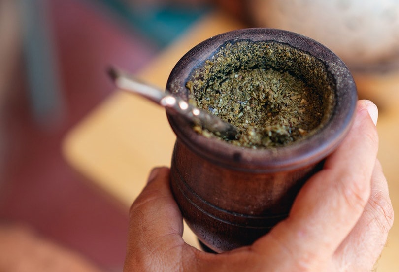 a male hands holding a wodeen cup of yerba mate