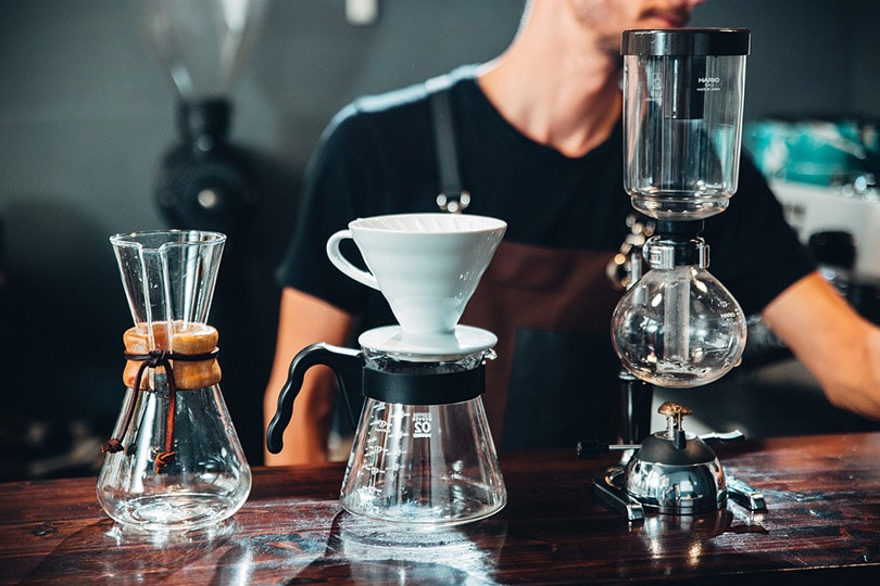 cropped barista in front of coffee brewers