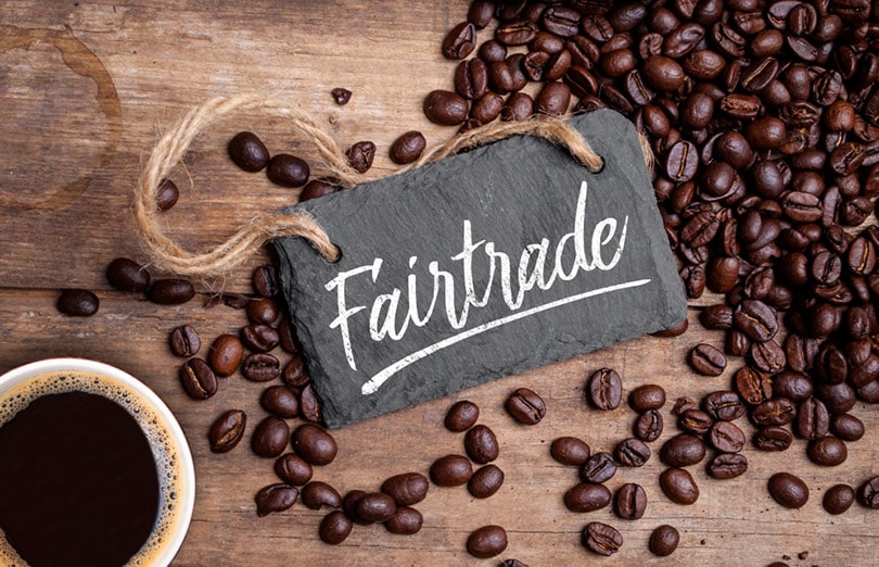 fair trade logo and coffee beans on wood