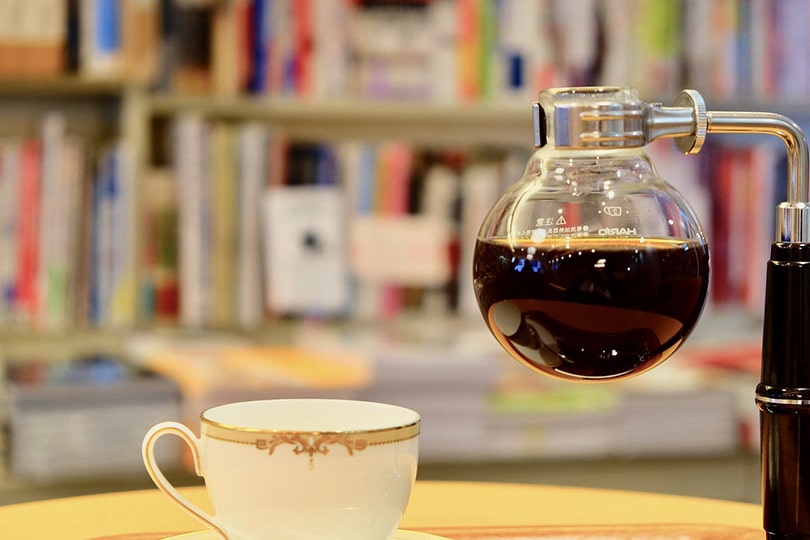 siphon coffee maker near a ceramic cup