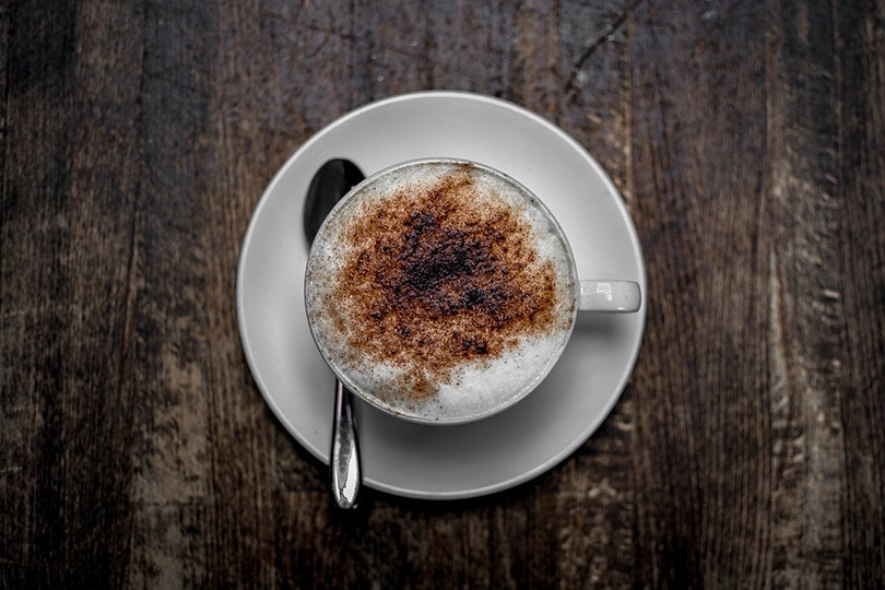 a cup of cappuccino on wooden table