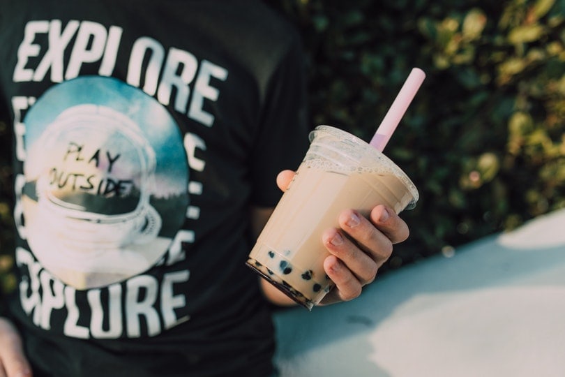 a person in black printed shirt holding a bubble tea
