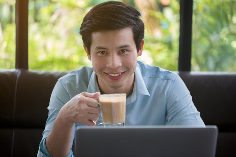 a young Asian man is drinking coffee in cafe