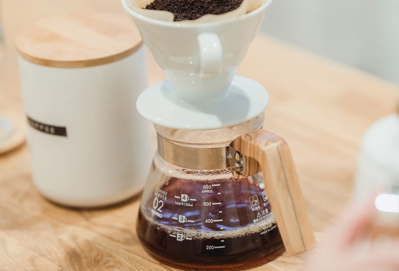 coffee pot on brown wooden table beside a ceramic cup