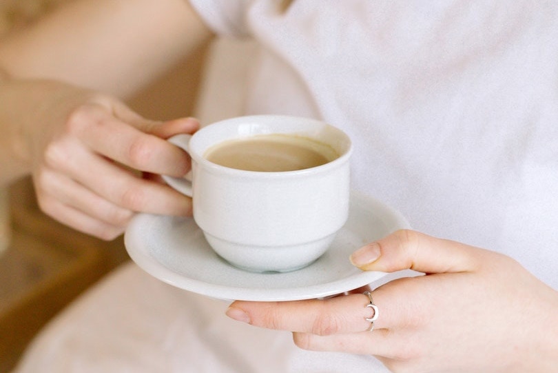 cropped woman holding a cup of coffee and saucer