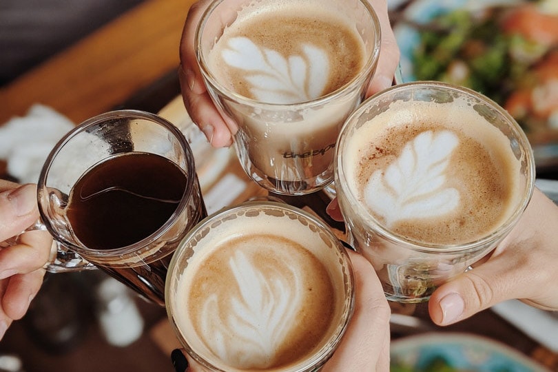 people with four drinking glasses of coffee making a toast