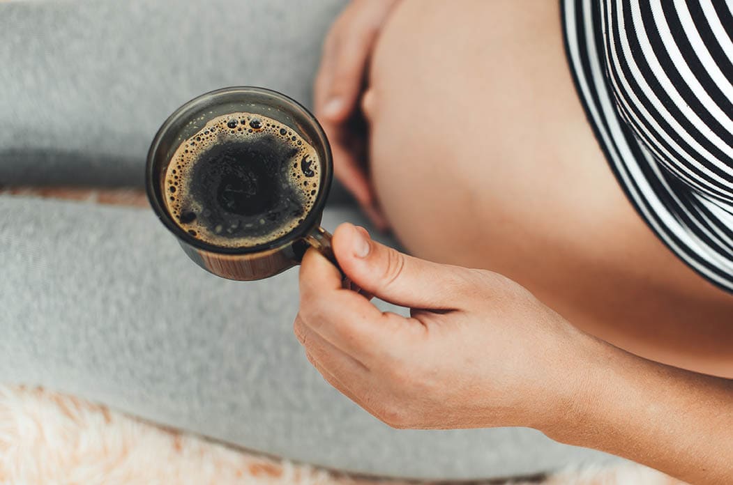 pregnant woman holding coffee