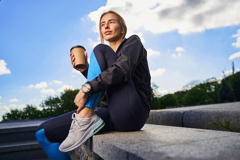 sporty woman having cup of coffee outdoors