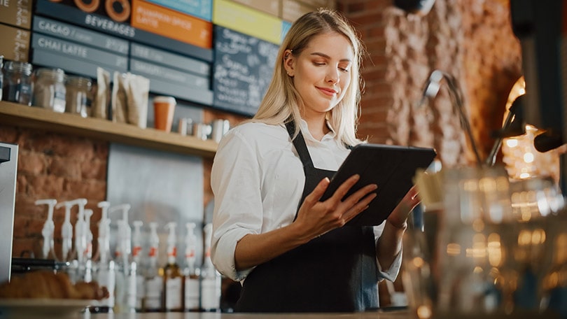 young caucasian coffee shop manager is making notes on a tablet computer