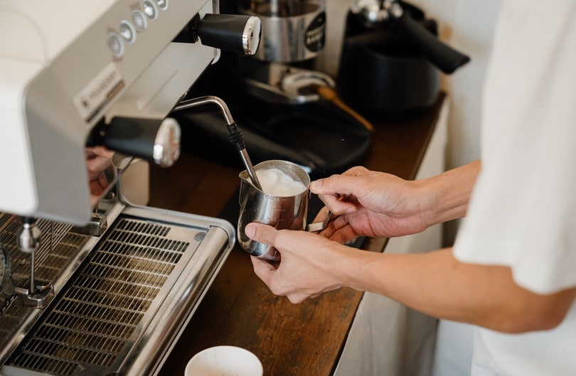 Barista frothing milk in a coffee shop