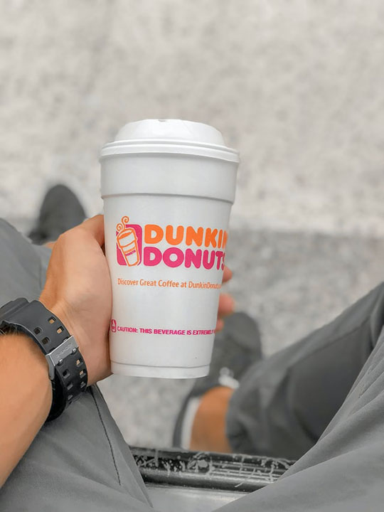 person holding a cup of Dunkin Donuts Coffee