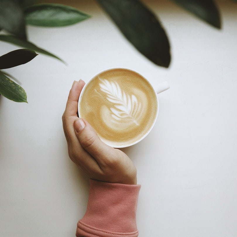 person holding white ceramic cup with coffee