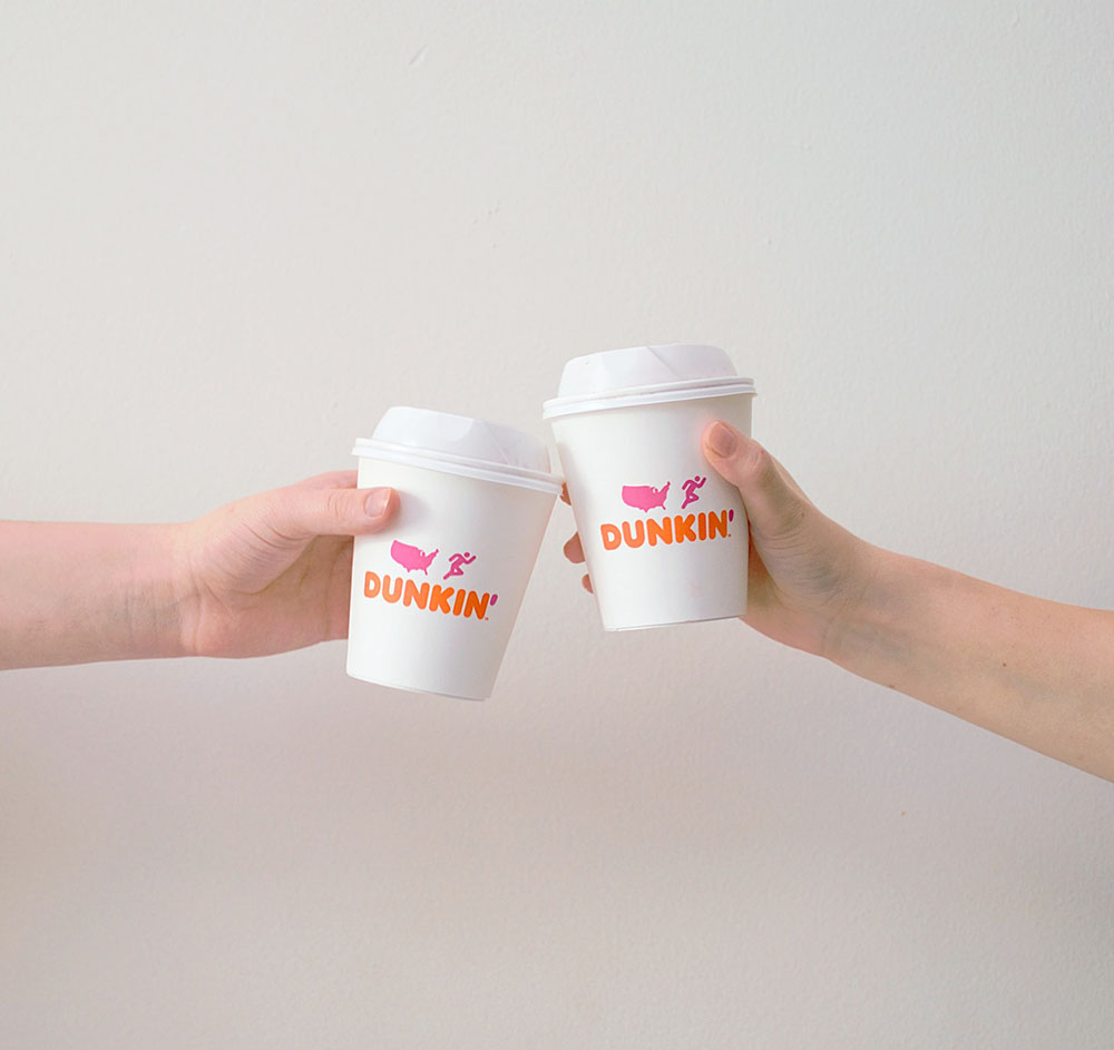 two people toasting their Dunkin Donut cups