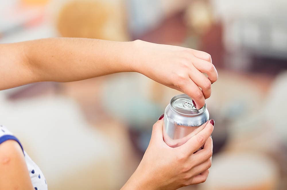 woman opening a can of energy drink