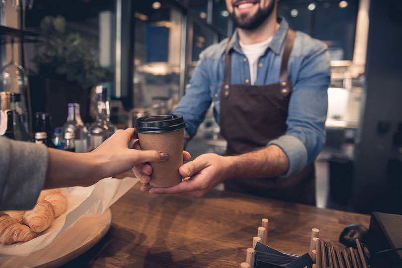female hand taking cup of hot coffee from barista