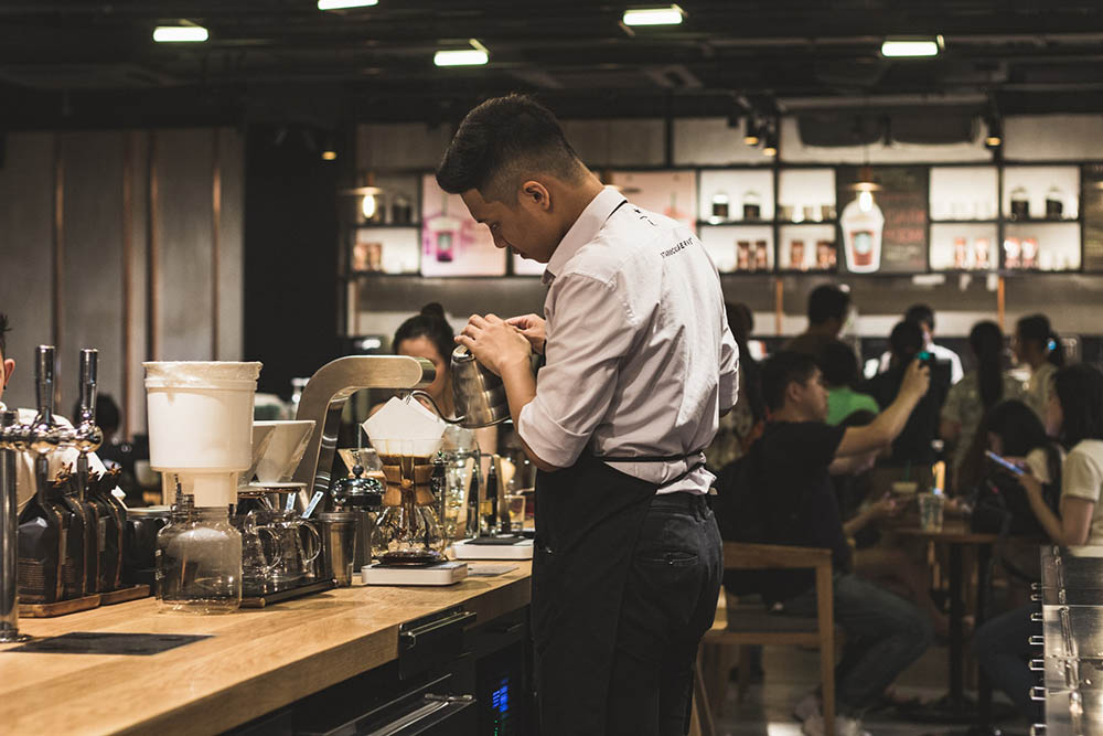 male barista preparing coffee in the cafe counter