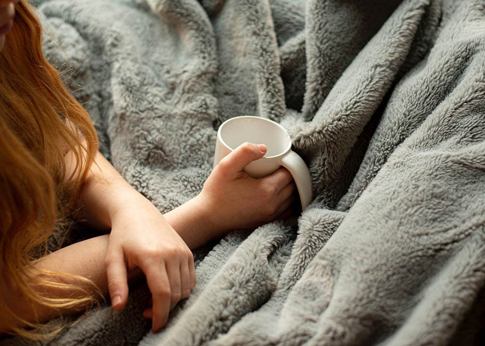 woman in bed holding an empty mug