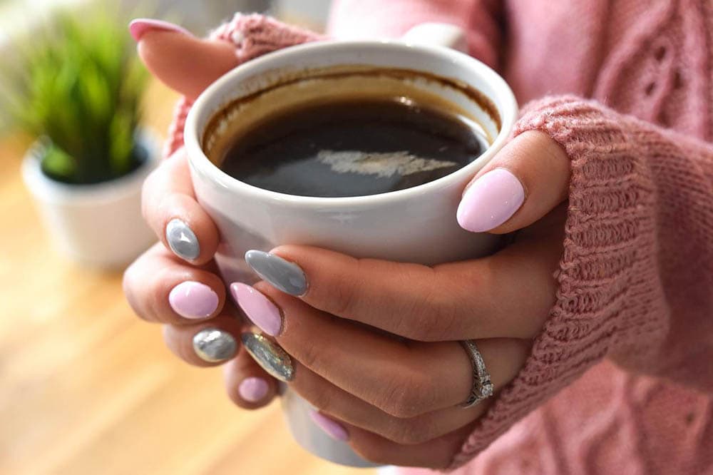 woman with polished nails having coffee
