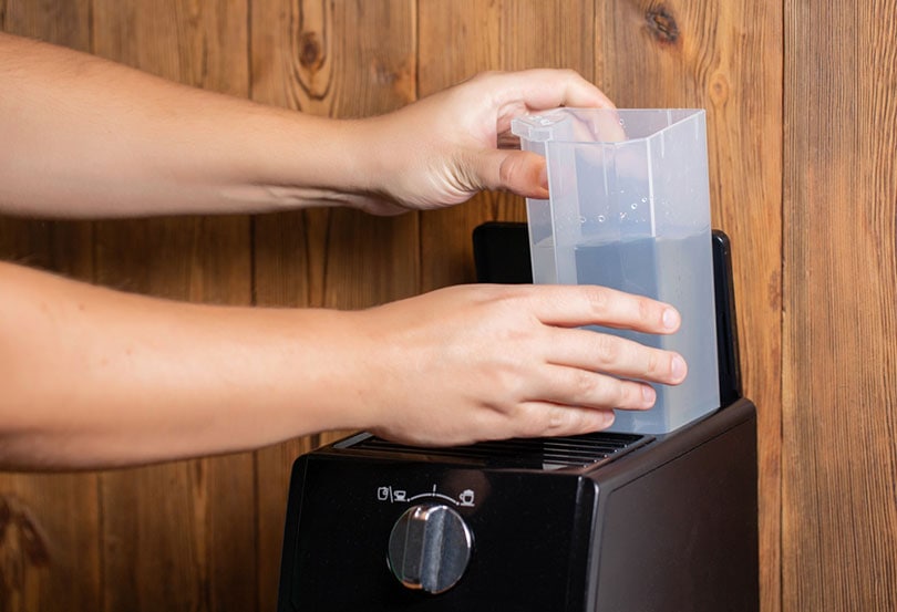 a man inserts a container of water into a coffee maker