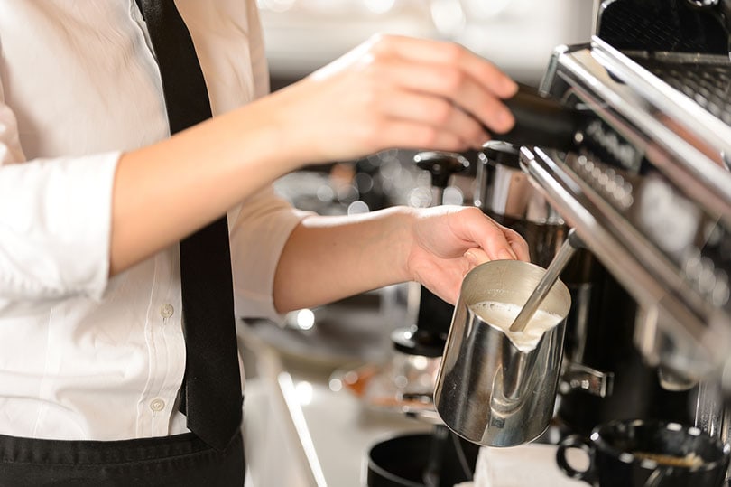 barista steaming milk in a cafe