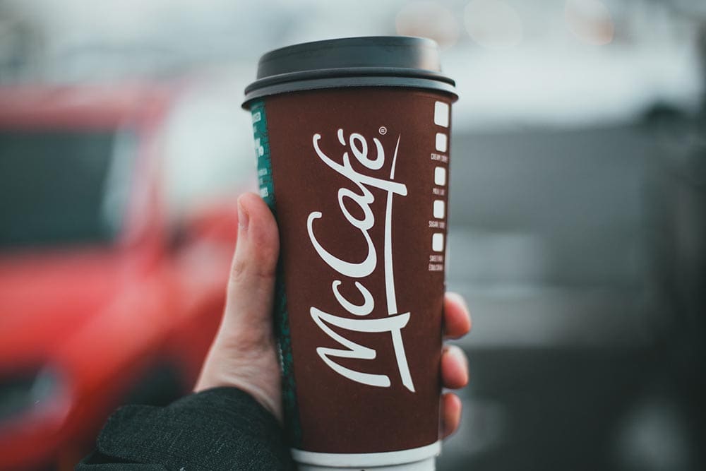 hand holding a cup of Mcdonald's McCafe coffee