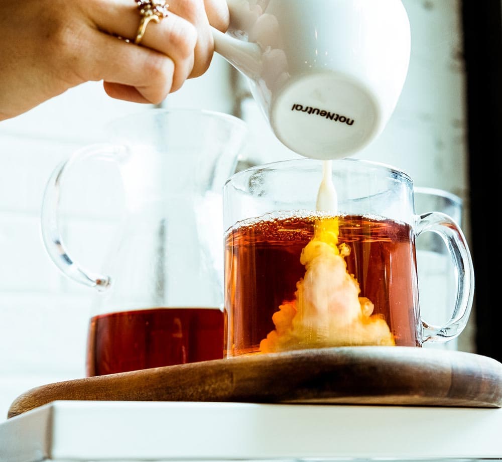 pouring creamer on a glass of coffee