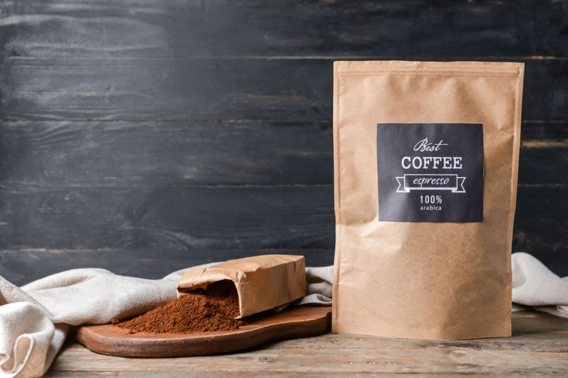 bags with ground coffee on wooden background