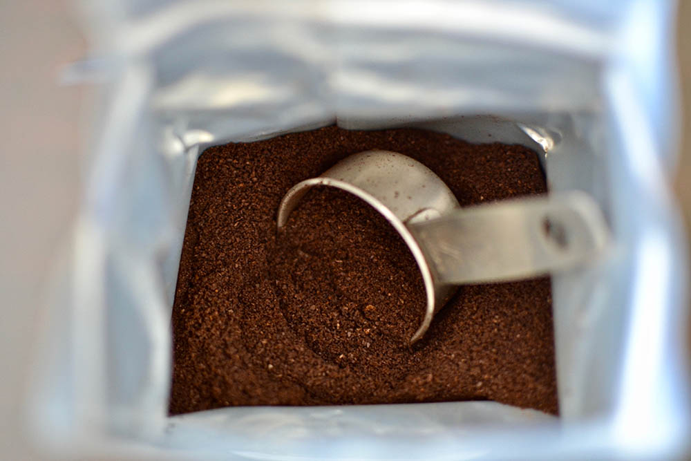 ground coffee and scooper inside the packaging