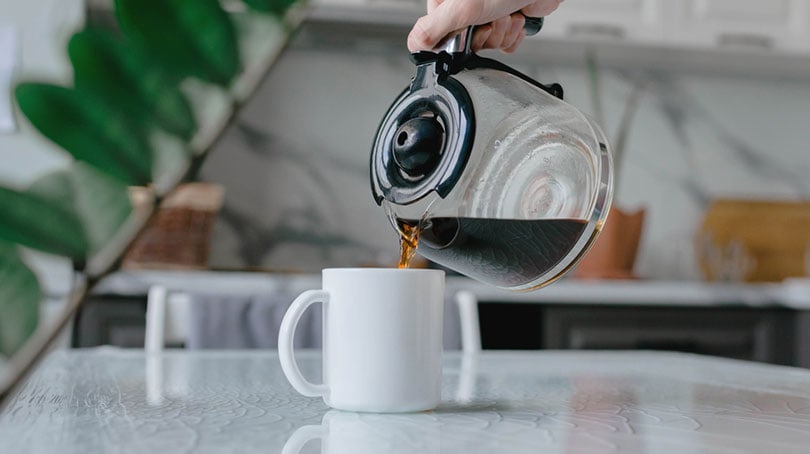 pouring brewed coffee into a mug