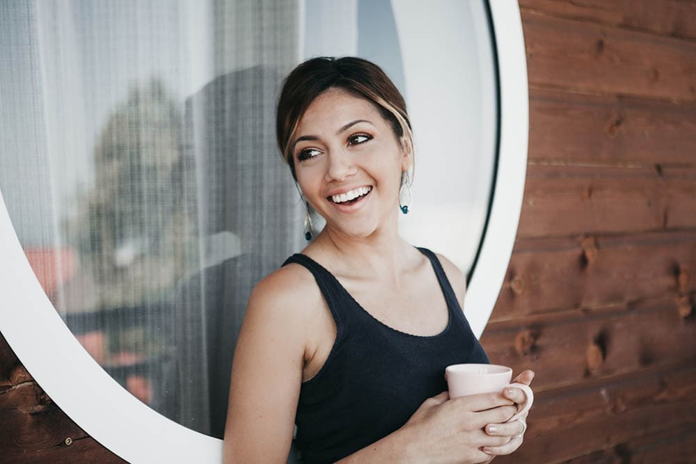 young woman smiling while holding a cup of coffee