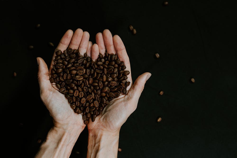 heart-shaped coffee beans in a person's palm
