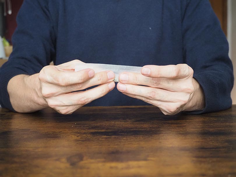 man rolling a joint paper with coffee