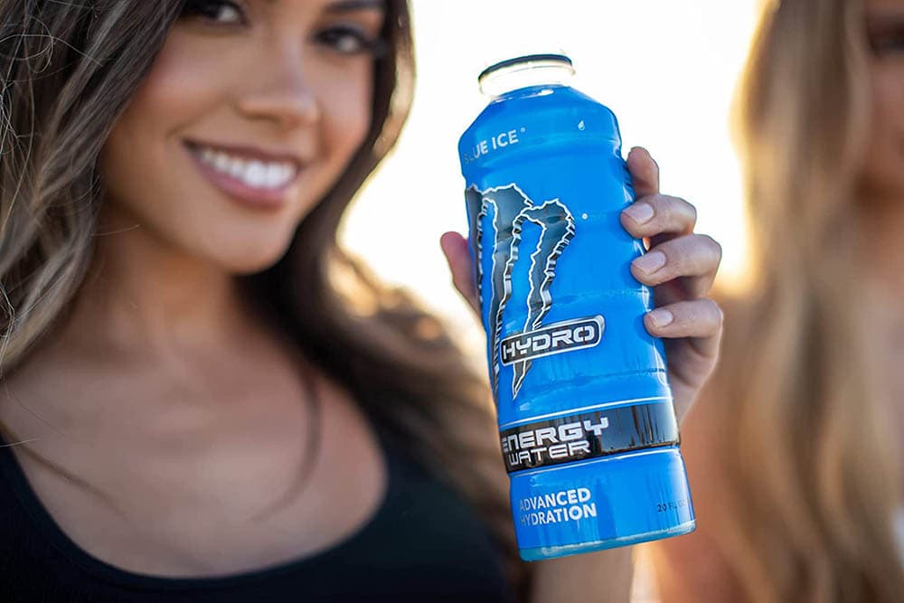 woman holding a bottle of Monster Energy Hydro Water Blue Ice