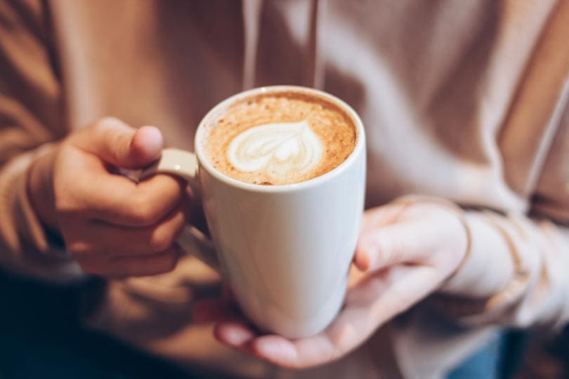 a cup of coffee cappuccino in female hands at cafe