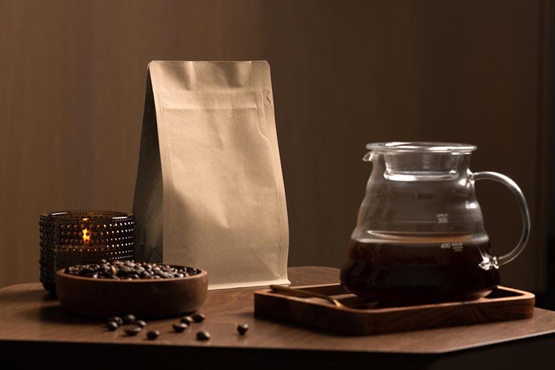 coffee packaging on a wooden table, with pot, candle, coffee beans in bowl