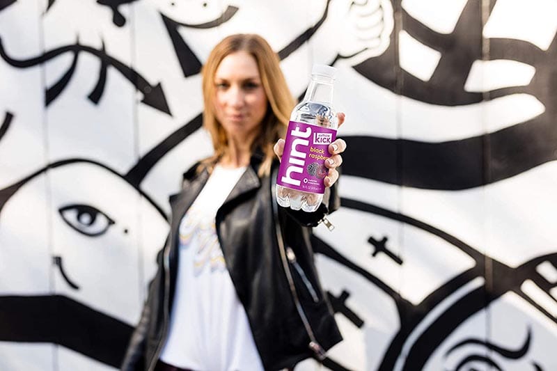 woman holding a bottle of Hint Kick with Caffeine Water Black Raspberry