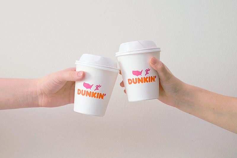 hands toasting dunkin coffee cups