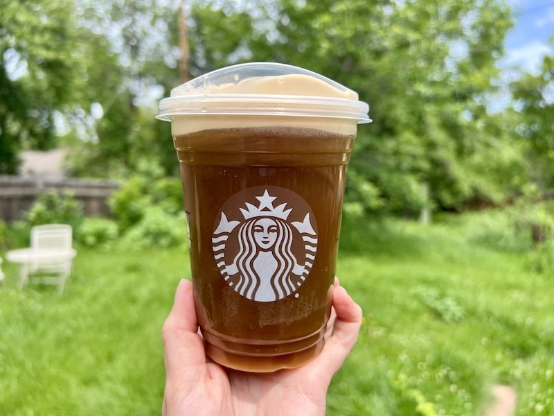 Starbucks honey almond milk nitro cold brew in front of green yard