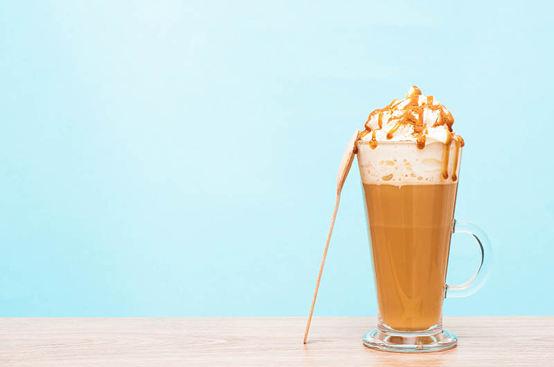 a glass of caramel coffee drink with whipped cream