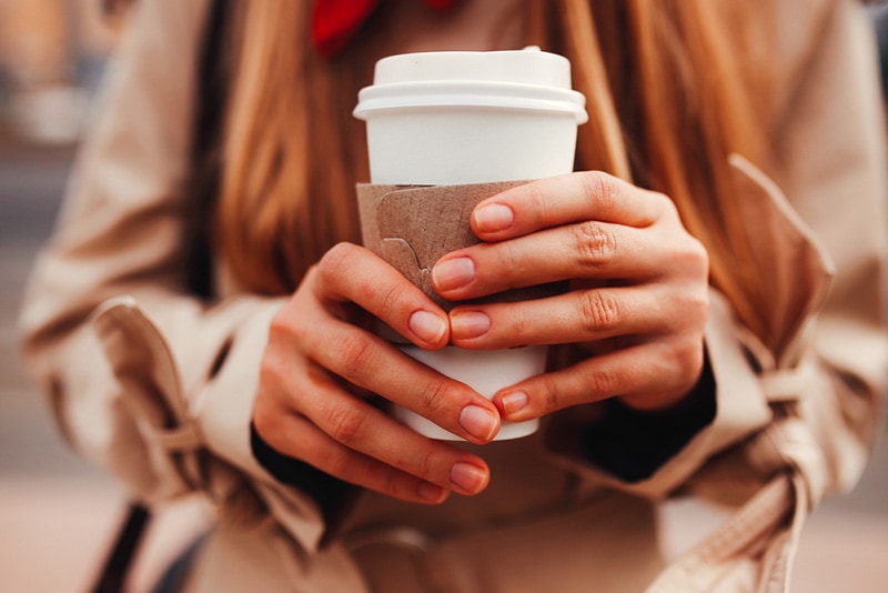 female hands holding a coffee in plastic cup