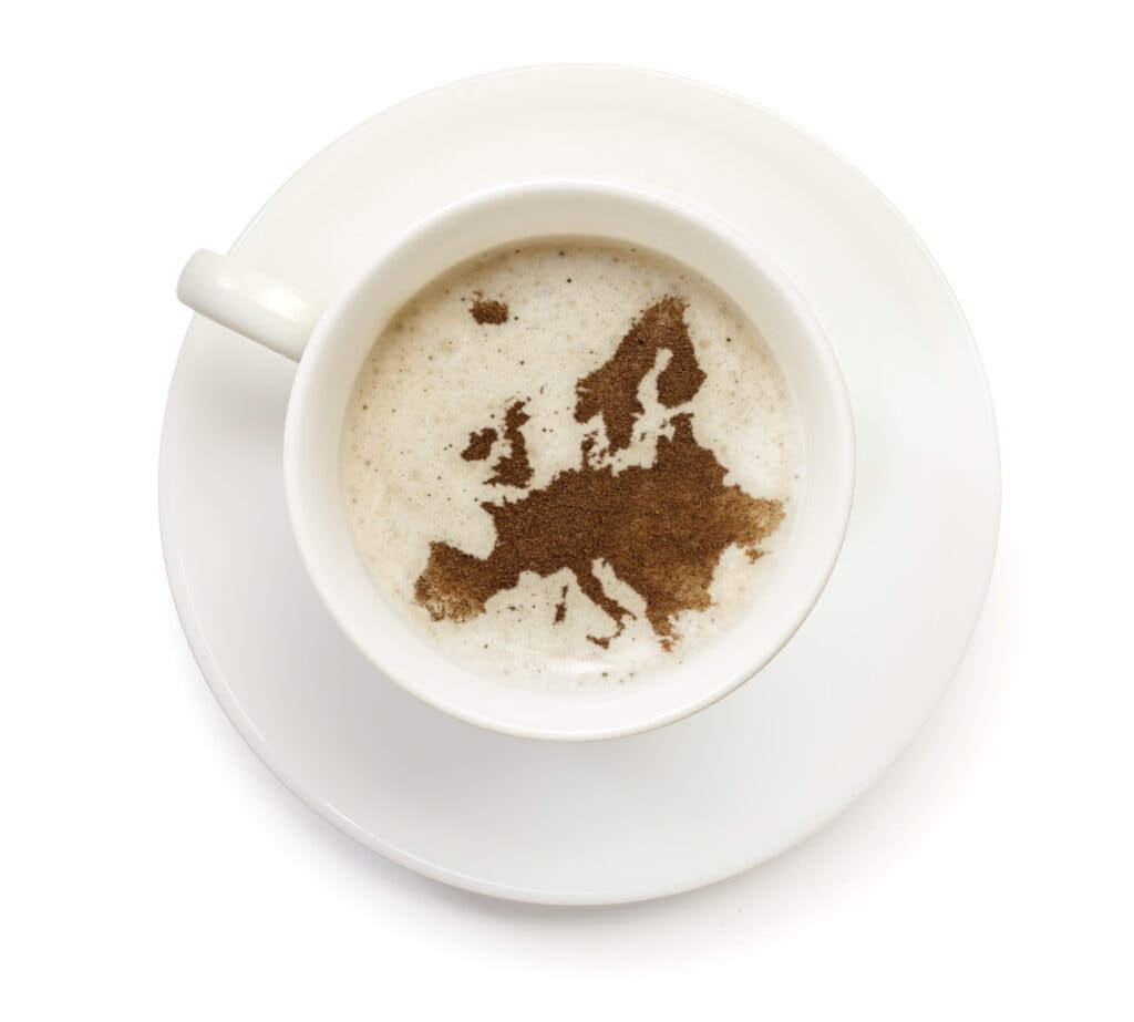 A cup of coffee with foam and powder in the shape of Europe